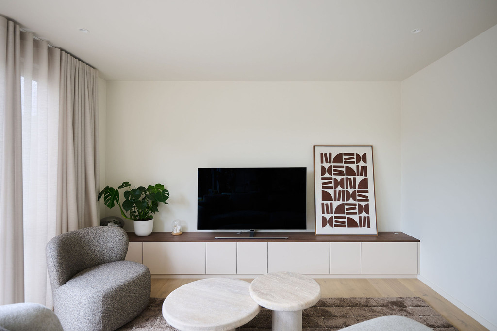 Meuble bas de télévision sur mesure en beige avec plateau foncé et décoration dans un salon moderne