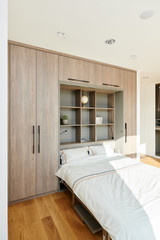 Opklapbed op maat met ingebouwde planken en opbergruimte in een moderne slaapkamer, optimaal gebruik van de ruimte.