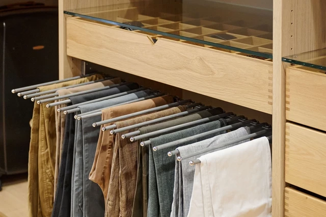 Op maat gemaakte kledingkast in U-vorm met speciale ophangrails voor het ordenen van broeken en een lade met glazen top.