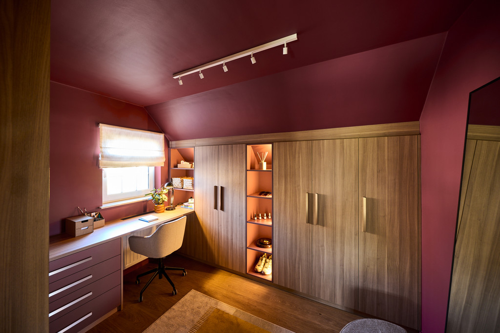 Dressing op maat onder schuin dak met houten afwerking, open nis met verlichting en geïntegreerd bureau